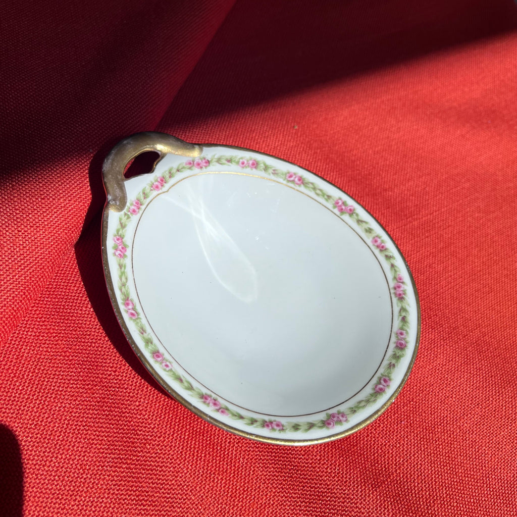 Small decorative plate with floral pattern on a red fabric background