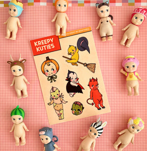 a sticker sheet of halloween-themed kewpie dolls on a flatlay with lots of kewpie dolls