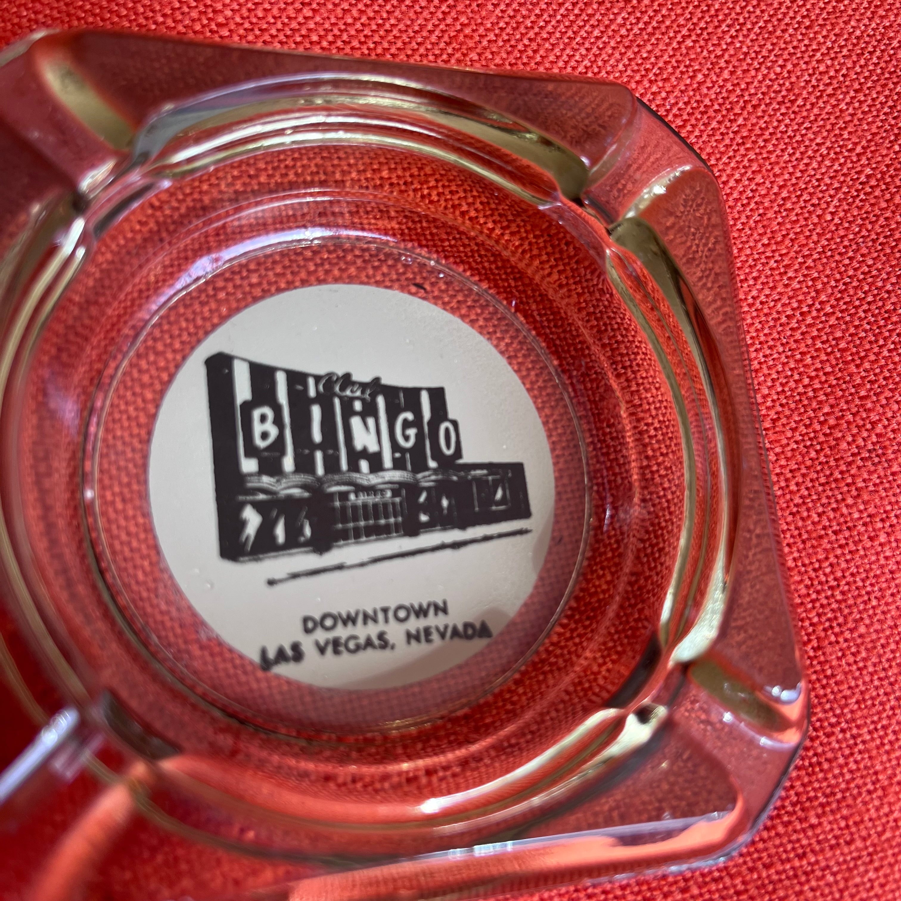 Clear glass ashtray with a label on a red background