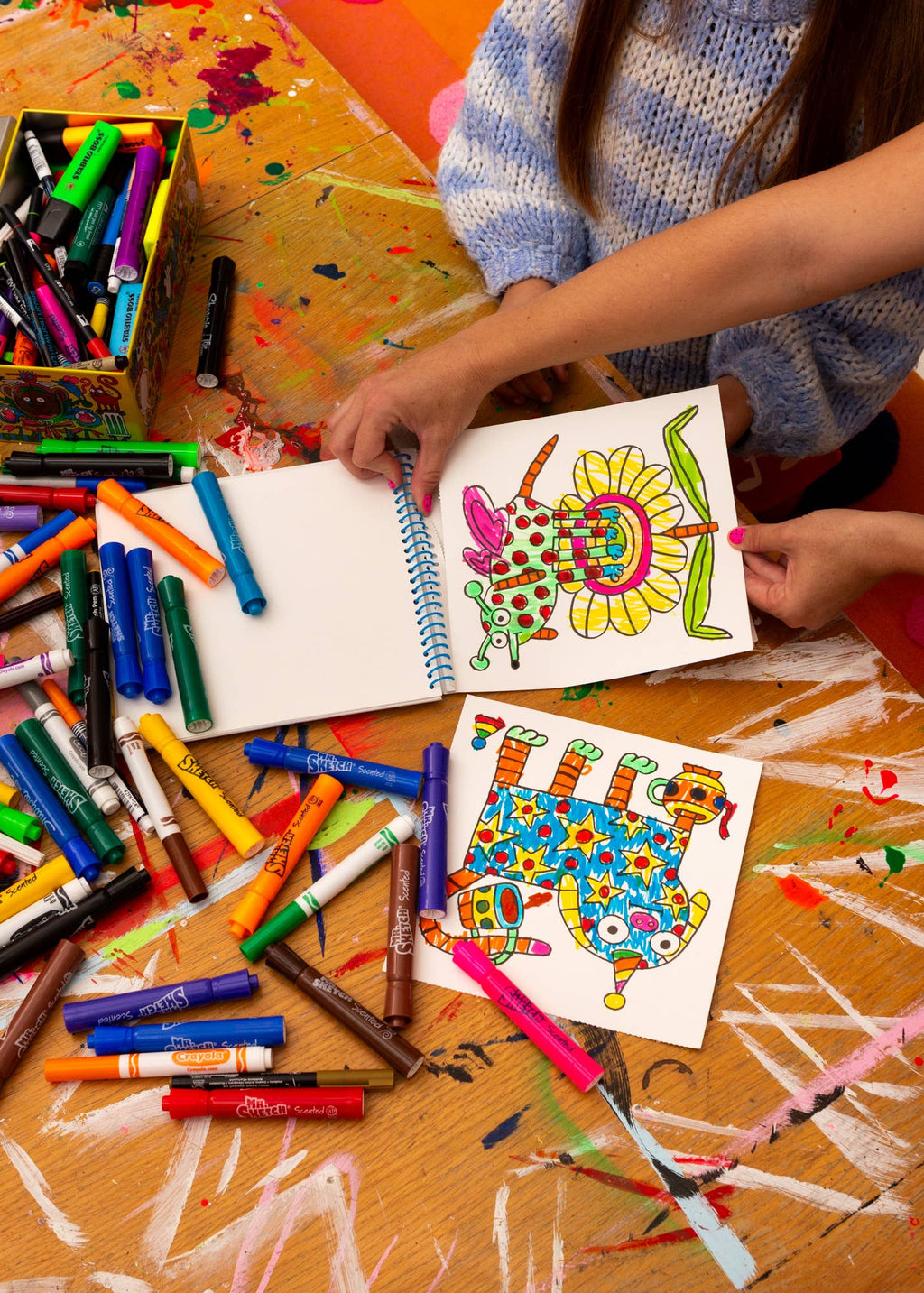 Colorful art supplies and children's drawings on a table.