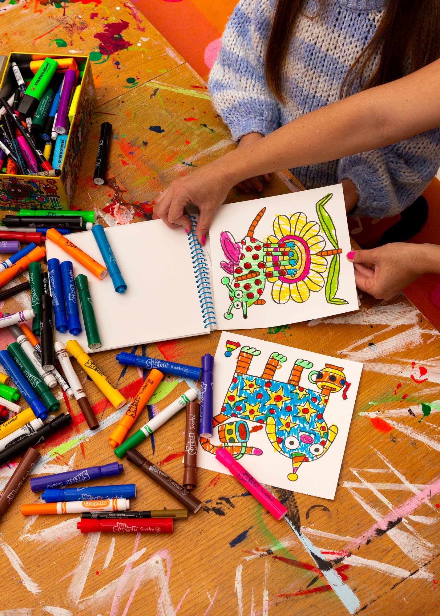 Colorful art supplies and children's drawings on a table.