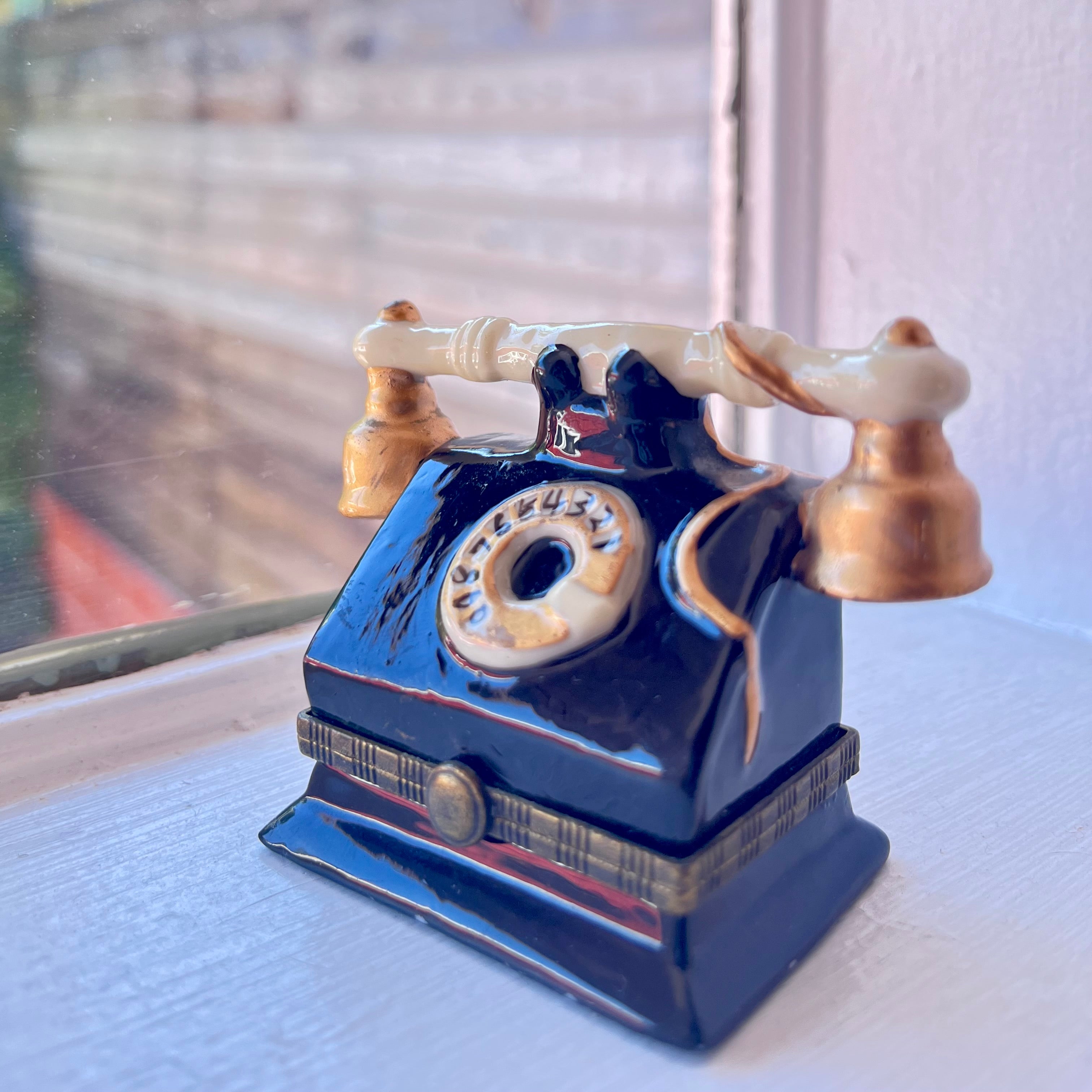 a vintage rotary phone shaped trinket box on a windowsill